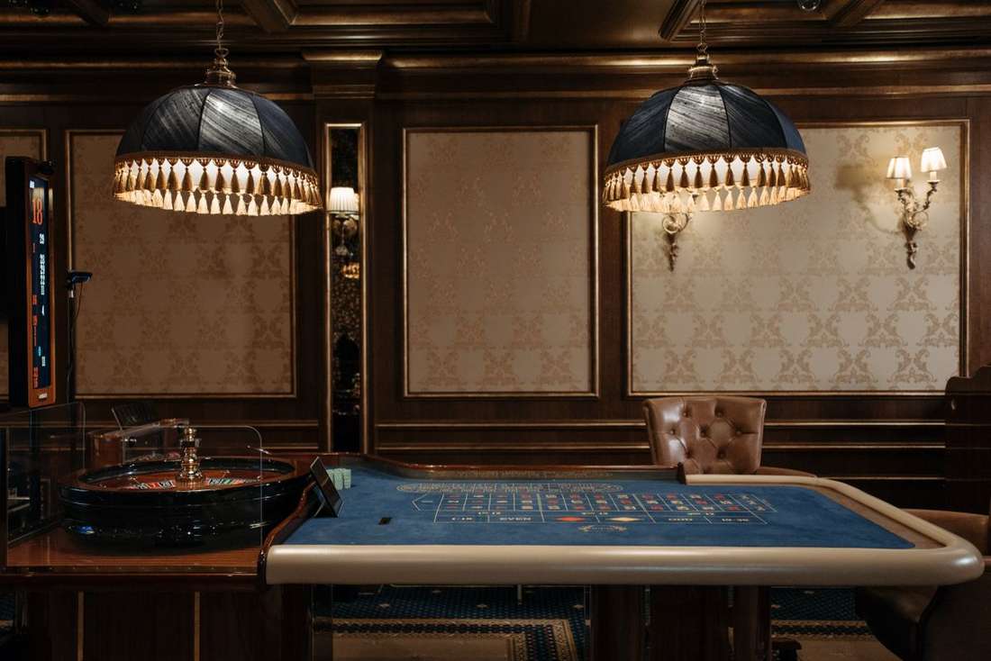 Interior kasino dengan meja roulette di bawah lampu hangat